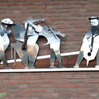 Wandskulptur von Musikanten, deren Silhouette aus silbernem Blech geschnitten ist