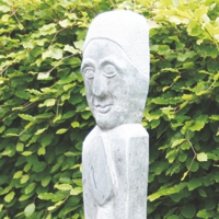 Stelenförmige Skulptur mit Gesicht aus weißem Stein