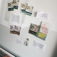Collage verschiedener bearbeiteter Papiere in einer Glasvitrine