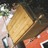 Holzcontainer in einem Baum hängend vor Wohnhäusern