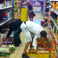 Foto von zwei Jugendlichen, die in einem Supermarkt Regale umräumen