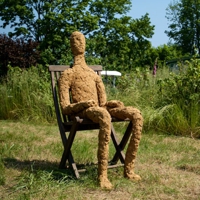 Lehmfigur auf einem Gartenstuhl