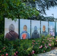 Plakate von Menschen in Rückansicht vor dem Meer