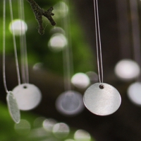 Kleine Aluminium-Plättchen an Nylonschnüren hängen in einem Baum
