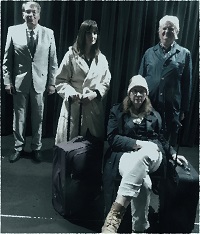 Vier Darstellende des Ensembles in schicker Kleidung und mit gepackten Koffern. Eine Person sitzt. Die anderen drei stehen dahinter.