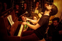 Der Musiker Kaum Jemand , alias Michael Holz, spielt am Klavier. Im Hintergrund sitzt das Publikum.