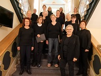 Die Chorleiterin Hajnalka Keveceg steht mit 14 Sängerinnen steht auf einer Treppe.