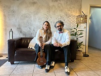 Die Musikerin NIKI und Prof. Dr. Ahmad Milad Karimi sitzen auf einem Sofa und schauen in die Kamera.