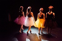 Die vier Performer/-innen des Stücks "Spectacular Failures" in Rückenansicht. Alle vier tragen ei-nen Petticoat und Hackenschuhe und bewegen sich auf das Publikum zu.