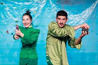 Szene aus der Vorstellung (Foto: Young-Soo Chang) Die Performerin Hannah Holthaus drückt eine Konfetti-Kanone, während der Performer Sefa Küskü auf einen roten Knopf drückt. Beide freuen sich.