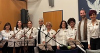 Ensemble und Chor Delnavazan aus Münster steht in aufgereiht mit ihren Instrumenten und Notenständern. Sie lachen in die Kamera.