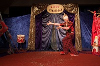 Der Clown fidelidad steht vor einem Vorhang in der Manege und bittet die Gäste hinein.