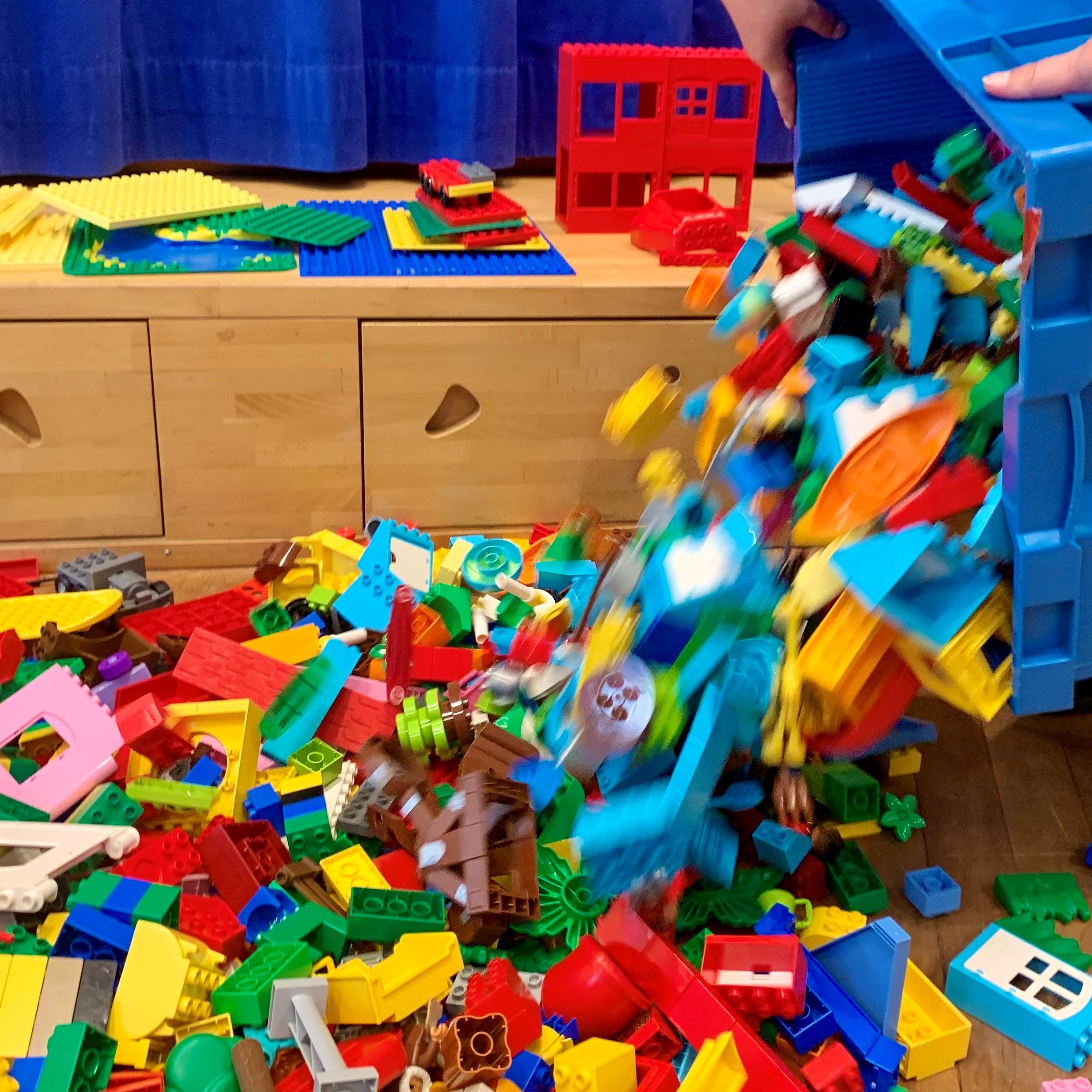 Aus einer Kiste werden LEGO® DUPLO® Steine ausgeschüttet.