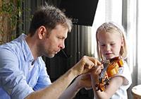 Musikschullehrer zeigt einem kleinen Mädchen, wie die Geige gehalten werden muss.