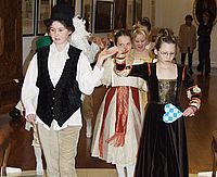 Kinder in barocker Kleidung führen einen Tanz auf.
