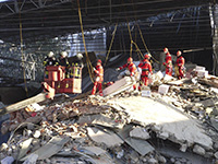 Höhenretter der Berufsfeuerwehr Köln hängen an Seilen über der Einsturzstelle und bergen Archivgut aus dem Schutthügel.