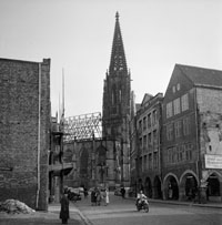 Schwarz-weiß-Foto von einer Straße und Häusern, im Hintergrund ist die Lambertikirche zu sehen.