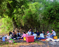 Gruppe von 15 asiatischen Menschen beim Picknick unter freiem Himmel