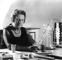 schwarze weiß Porträtfoto von Hanne Nüte-Kämmerer am Schreibtisch sitzend mit einem ihrer Kunstwerke