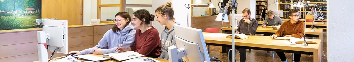 Junge Menschen an Arbeitstischen im Lesesaal