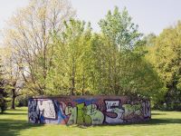 Kunstwerk Sanctuarium - eine kreisrunde Mauer mit Graffiti, innerhalb der Mauer wachsen Bäume