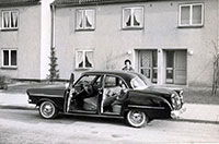 Foto von einer englischen Familie im Auto vor einem Wohnhaus