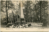 Das Ketteler-Denkmal im Schlossgarten: Obelisk aus Stein, am Boden liegen viele Kränze mit großen Schleifen (Foto von 1903).