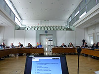 Blick in einen Sitzungssaal mit diskutierenden Menschen