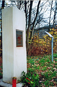 Kerze und Blumengebinde am Gedenkstein