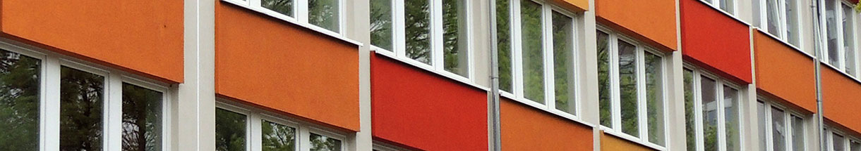 Hausfassade mit roten und orangefarbenen Flächen zwischen den Fenstern