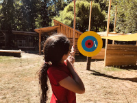 Ein Mädchen zielt mit Pfeil und Bogen auf eine Zielscheibe
