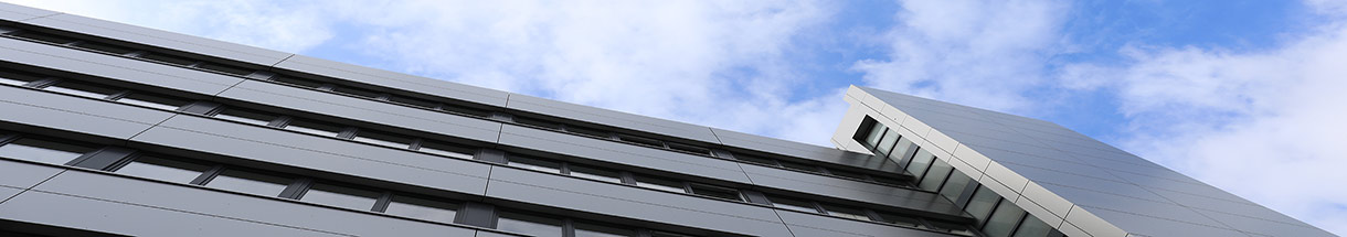 Silbergraue Metall-Fassade des Gebäudes an der Hafenstraße, darüber blauer Himmel