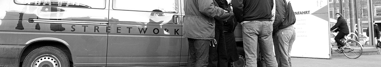 Schwarz-weiß-Foto (Ausschnitt): Mehrere Personen vor einem Auto mit 'Streetwork'-Schriftzug