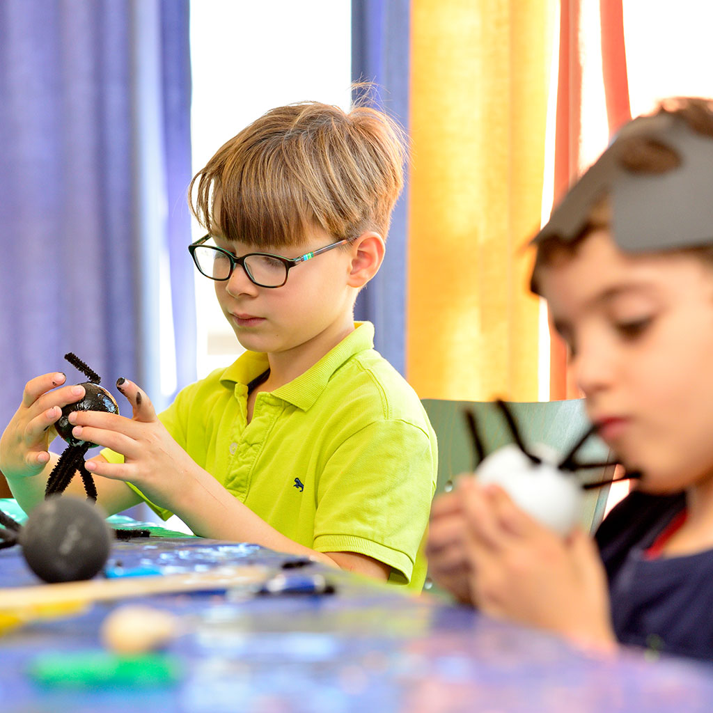 Zwei Kinder sitzen am Tisch und basteln