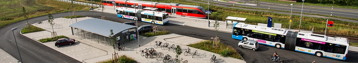 Schrägluftbild auf einen Platz mit Bussen und abgestellten Fahrrädern, im Hintergrund Gleise