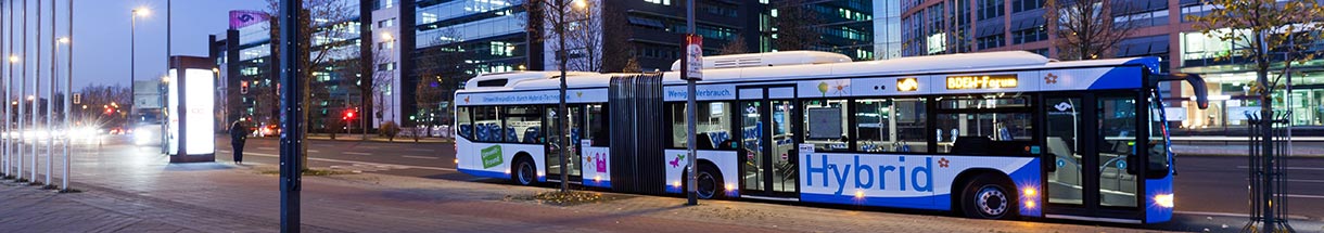 Bus mit der Aufschrift 'Hybrid' an einer Haltestelle