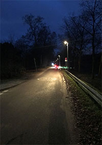 Foto, auf dem die intelligente Beleuchtung im Praxistest dargestellt ist: Zu sehen sind zwei Radfahrende bei Dunkelheit, der Kanalseitenweg wird durch die intelligente Beleuchtung jedoch ausgeleuchtet