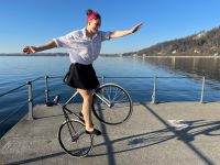 zu sehen ist eine Frau, die auf einem Fahrrad ein Kunststück aufführt