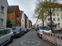 Schillerstraße in Münster: Zu sehen ist eine Fahrbahn auf der beidseitig Autos parken und dazwischen eine Gruppe Radfahrender unterwegs sind.
