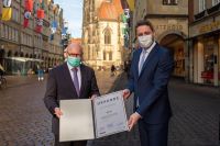 Oberbürgermeister Markus Lewe und Stadtbaurat Robin Denstorff halten die Verlängerungsurkunde der AGFS in der Hand (Foto: Meike Reiners)
