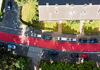 Luftbild: eine rote Fahrbahn zwischen Häuserreihen