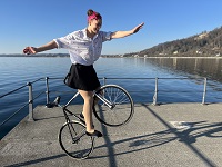 Auf dem Bild ist Antonia Bärk, die seit 2014 Weltmeisterin im Kunstradfahren ist, auf einem Fahrrad mit einem Kunststück abgebildet.