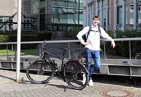 Vor dem Gebäude des Amtes für Mobilität und Tiefbau ist der Praktikant Steffen Goldhammer abgebildet mit einem Fahrrad