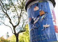 Auf einer Litfaßsäule klebt ein Plakat mit der Aufschrift Schmuddelwetterkampagne. Blau hinterlegtes Plakat auf dem Fahrradfahrer skizziert sind die die Beine hochheben; im oberen Bild sind 2 Häuser skiziert.