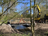 Seitliche Ansicht der Brücke; rechts ein gelber Kran der die Holzstreben einsetzt.