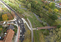 Blick auf die Straße, daneben der Geh- und Radweg mit dem angrenzenden Flusslauf.