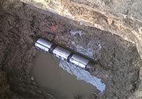 Freigelegte Wasserleitung mit drei Metallschellen