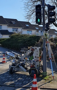 Ein spezielles Prüfgerät steht vor einem Ampelmast.