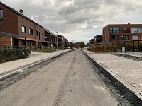Mittig die noch nicht asphaltierte Straße. Links der Gehweg und rechts Parkbuchten.