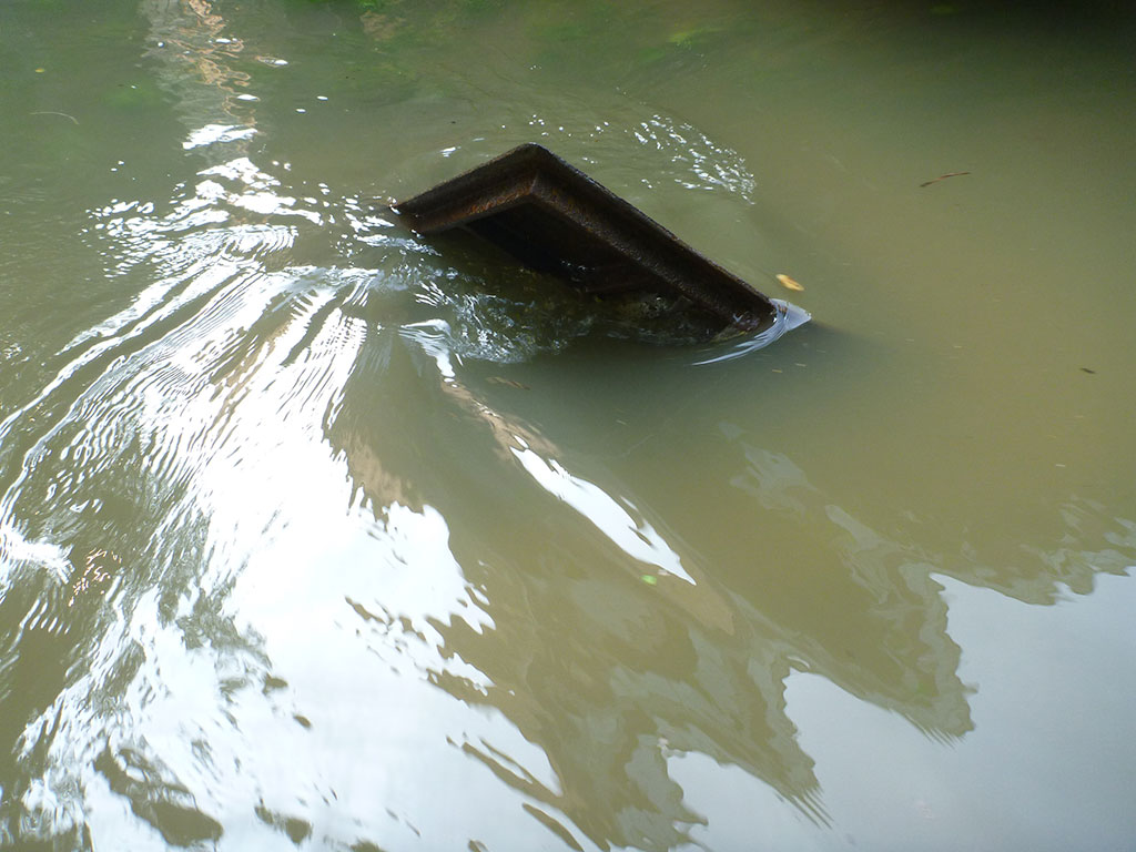 Das Gitter eines Straßenablaufs bei Hochwasser